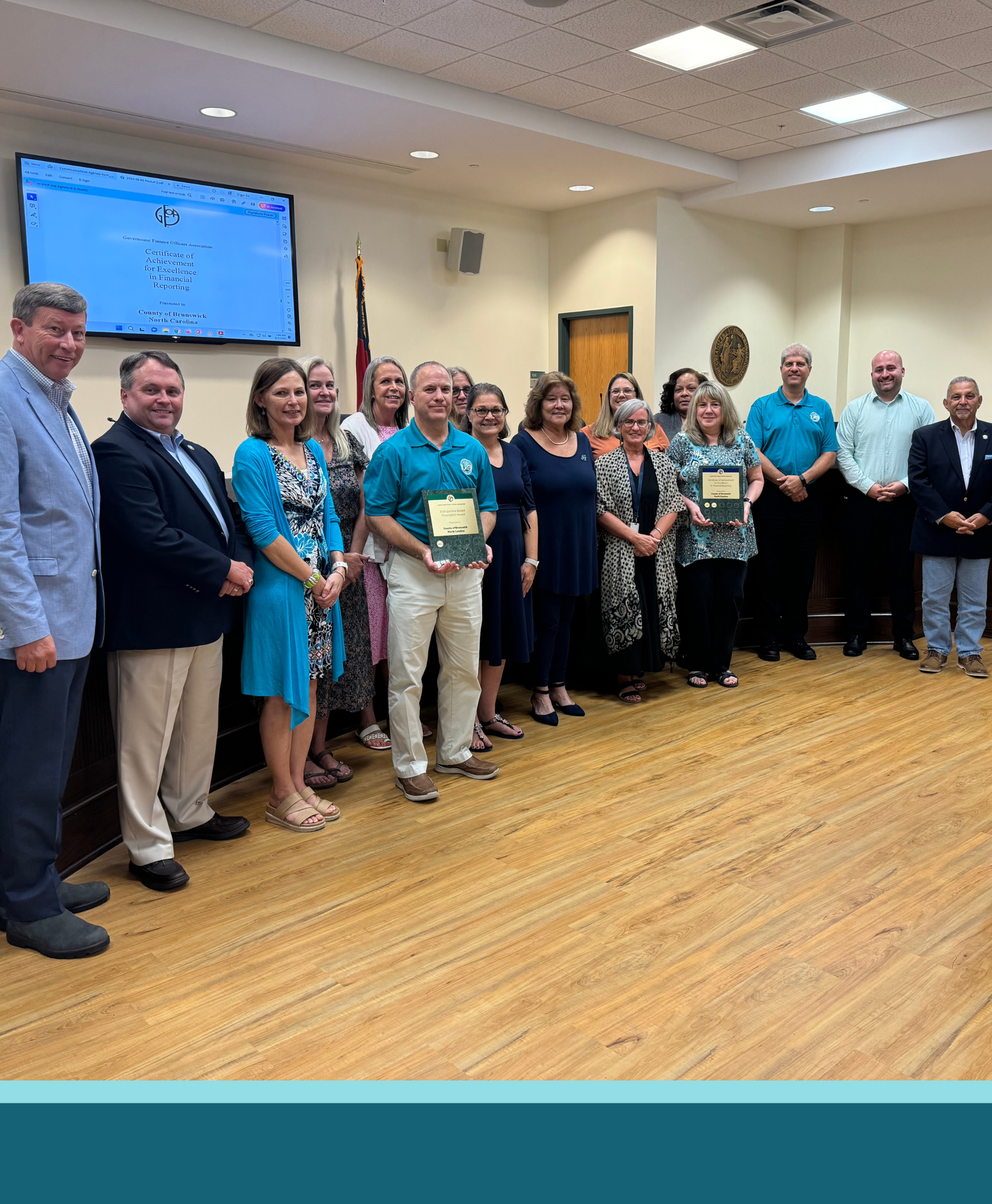 Brunswick County Commissioners and Finance staff standing together while holding two awards.